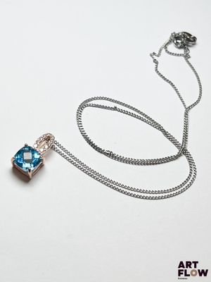 une chaîne en argent à laquelle est accroché un pendentif bleu et blanc