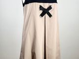 beige and black dress with a bow on a mannequin base