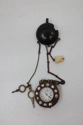 a clock that is attached to a chain on the wall
