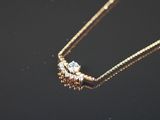 un gros plan d'un collier en or orné de deux diamants, sur un fond noir