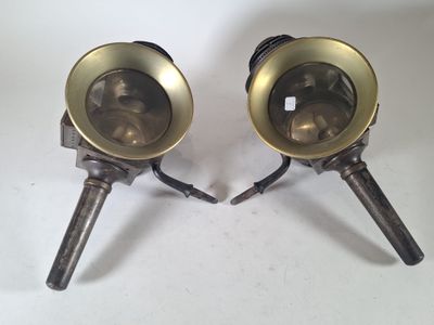 une paire de lampes anciennes en laiton reposant sur des pieds tripodes, sur fond blanc