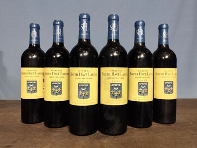 six bottles of red wine are lined up on a table