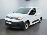 La camionnette blanche est garée dans une grande pièce au sol noir.