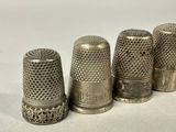 three silver thimbles are lined up in a row on a white surface