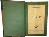 un vieux livre à la couverture verte, ouvert sur une surface blanche