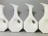 quatre vases blancs sont alignés sur une table