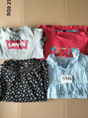 trois t-shirts et une jupe posés sur un carton