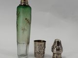 a green glass bottle and a silver cup sitting next to each other