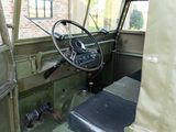 steering wheel and dashboard of an old military vehicle with a brick building in the background