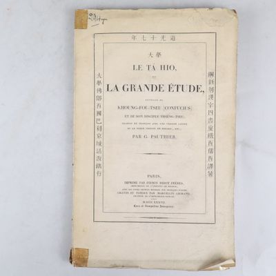 un vieux livre posé sur une table à côté d'un mur blanc