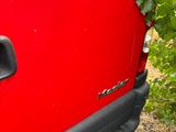 a red jeep with a bunch of vines growing on the side of it