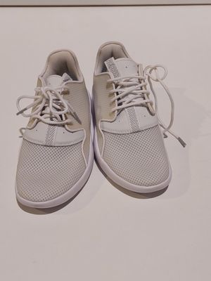une paire de baskets blanches à lacets posée sur une surface blanche