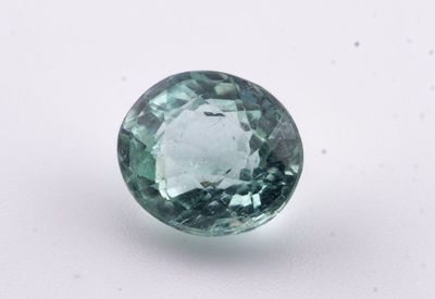 un gros plan d'un saphir vert posé sur une surface blanche