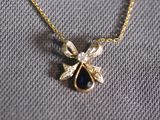 a close up of a gold necklace with a blue tear on it