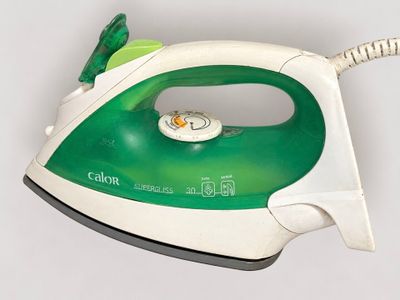 a green and white steam iron sitting on a white surface