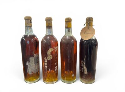 quatre bouteilles d'alcool sont alignées sur une surface blanche