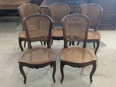 four chairs with wicker back and cane back are in a room