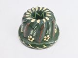 a green and yellow cake shaped candle holder on a white surface