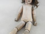 une poupée en bois assise par terre sur un fond blanc