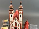 une petite maison de poupées avec un toit rouge et deux tours