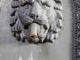 a statue of a lion with a water fountain in front of it