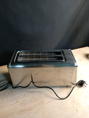 un grille-pain argenté posé sur une table devant un fond noir