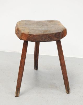 un vieux tabouret en bois posé sur un sol en béton