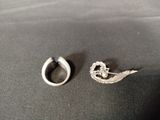 a silver ring and a silver earring on a black surface