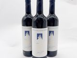 trois bouteilles de vin rouge posées sur une table blanche