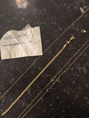 three different types of gold necklaces on a table with a piece of paper