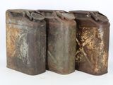 three old rusty metal cans sitting next to each other on a white surface