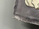 Quelqu'un est en train de coudre un coussin sur lequel est représenté un chien.