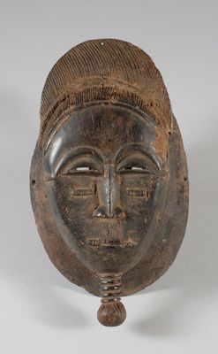 une image représentant un masque en bois posé sur un support, sur une surface blanche