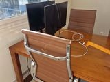a desk with two computers and a chair in front of a window