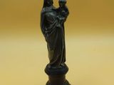 une statue noire représentant une femme tenant un enfant dans ses bras, posée sur une table