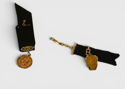 two pieces of jewelry that include a medal and a keychain