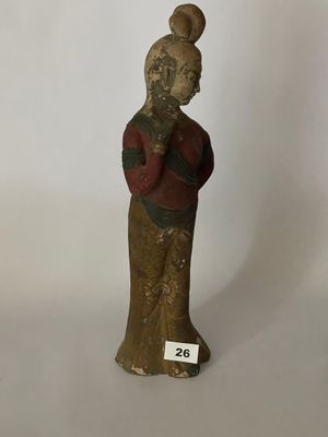 une vieille statue en bois représentant une femme portant un chapeau et une chemise rouge