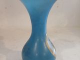 a blue vase with a gold rim sitting on a white surface