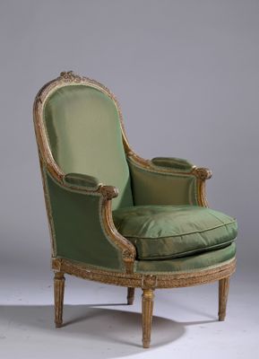 une vieille chaise avec une assise rembourrée verte et des bordures dorées