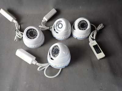 four white cameras sitting on top of a table next to a cell phone