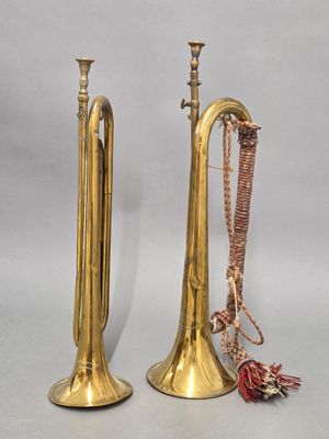 pair of brass trumpets with tassels on a gray background