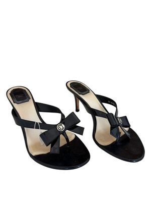 une paire de sandales noires avec un nœud au talon