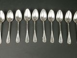 six cuillères en argent sont alignées sur une surface noire