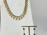 un ensemble composé d'un collier et de boucles d'oreilles en or, posé sur un socle en marbre