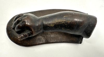 sculpture en bronze représentant une main posée sur une plaque en bois