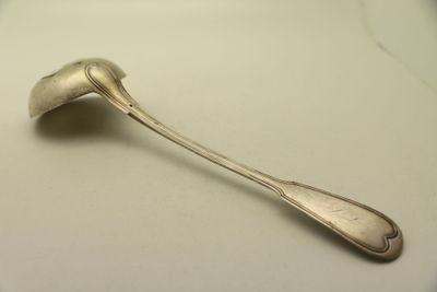 une cuillère en argent posée sur une assiette blanche, sur une surface blanche