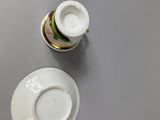 a white cup and saucer with a sandwich on it