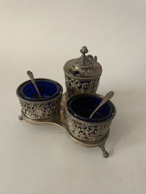 deux récipients en verre argenté et bleu, accompagnés de cuillères, posés sur une surface blanche