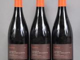 three bottles of red wine sit on a table in front of a gray background