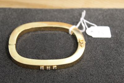 a close up of a gold bracelet with a tag on it
